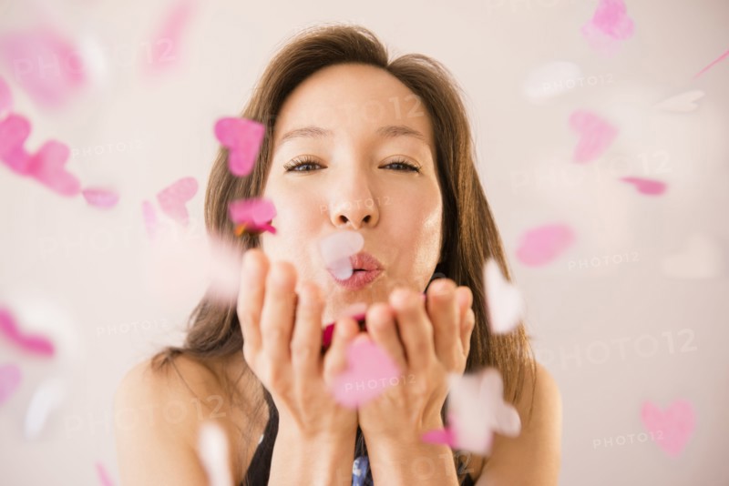 Mixed race woman blowing confetti