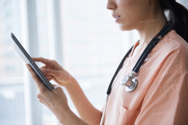 Mixed race nurse using digital tablet