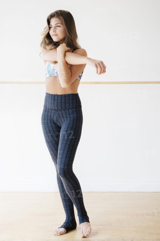 Mixed race dancer stretching in studio