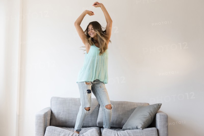 Mixed race woman jumping on sofa