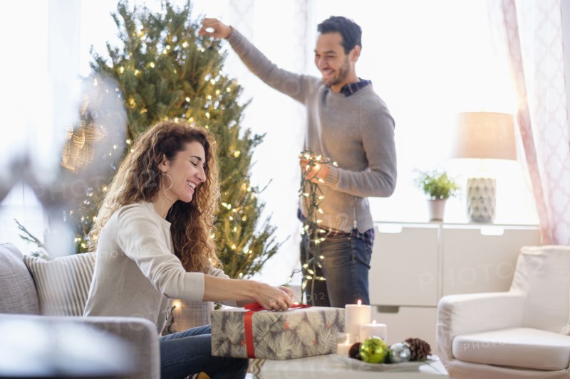 Couple decorating for Christmas in living room