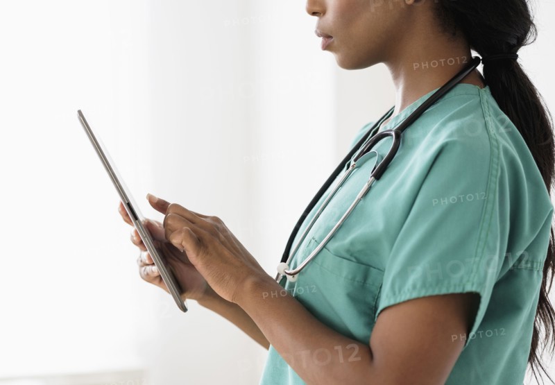 Mixed race nurse using digital tablet