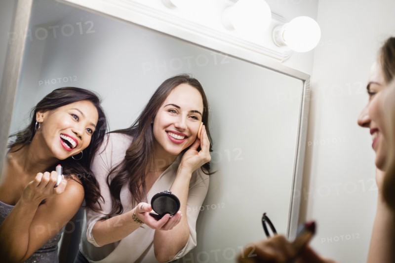 Women applying makeup in mirror
