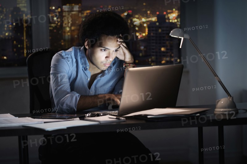 Mixed race businessman working late in office