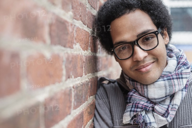 Mixed race man leaning on brick wall