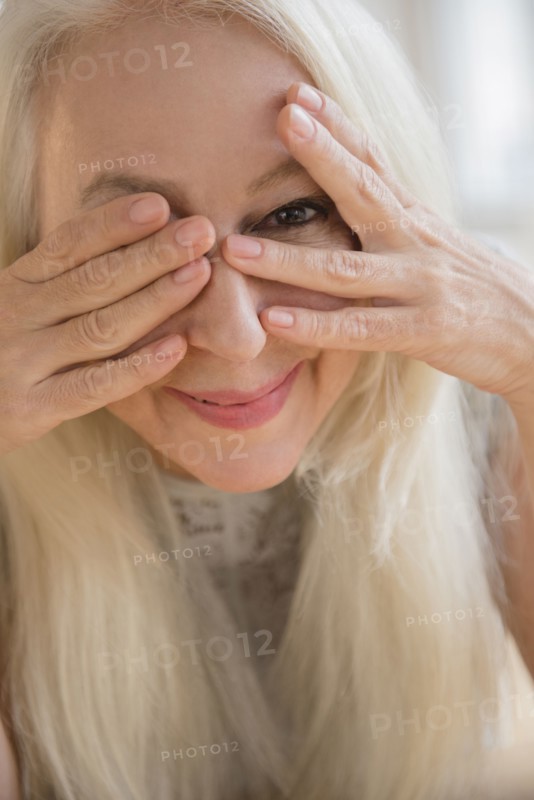 Caucasian woman peeking from behind eyes