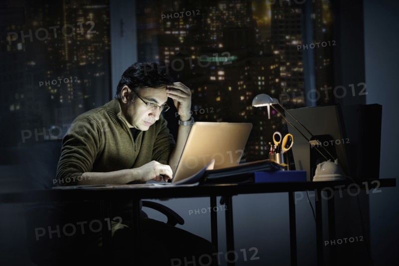 Mixed race businessman working late in office