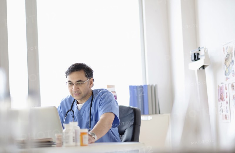 Mixed race doctor working on laptop