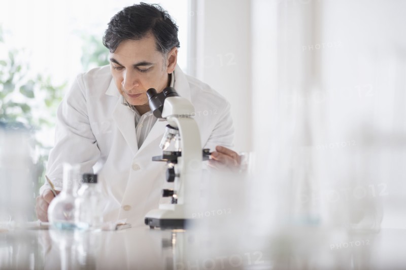 Mixed race scientist using microscope in laboratory