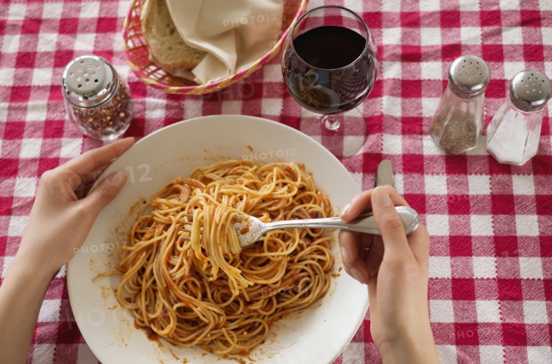 Hispanic woman eating plate of pasta