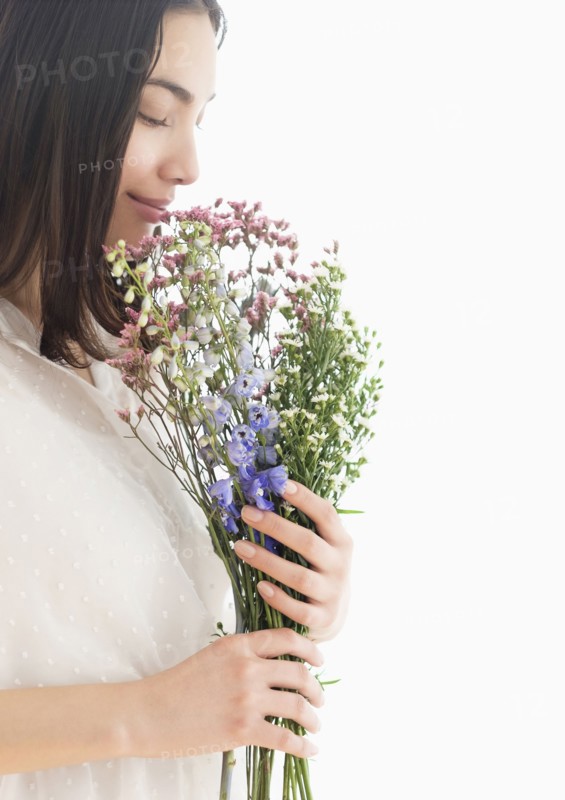 Hispanic woman smelling bouquet of flowers