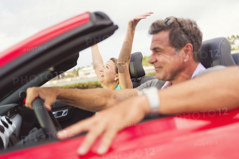 Caucasian couple driving convertible