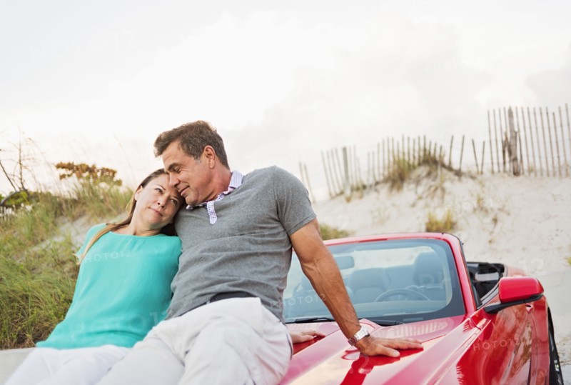 Caucasian couple sitting on convertible