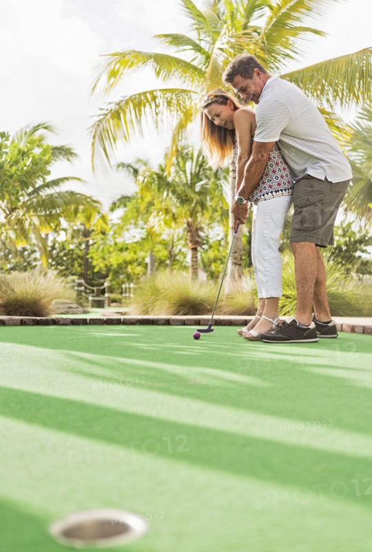 Caucasian couple playing miniature golf