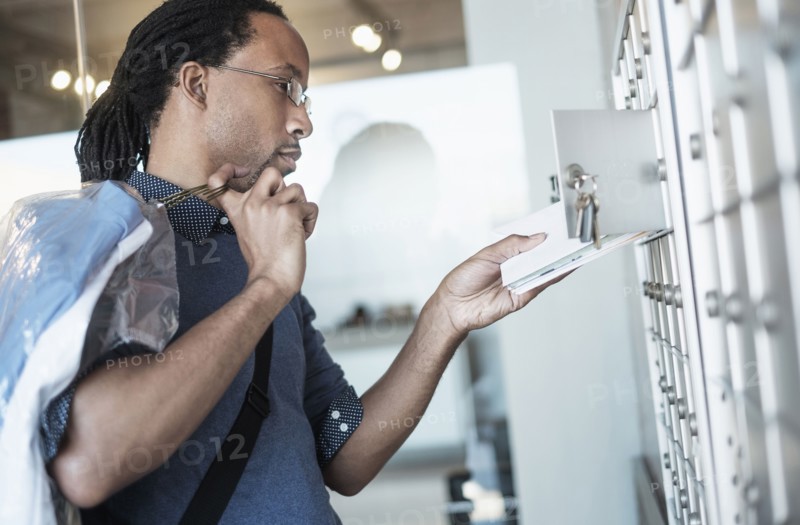 Black man gathering mail from post office box