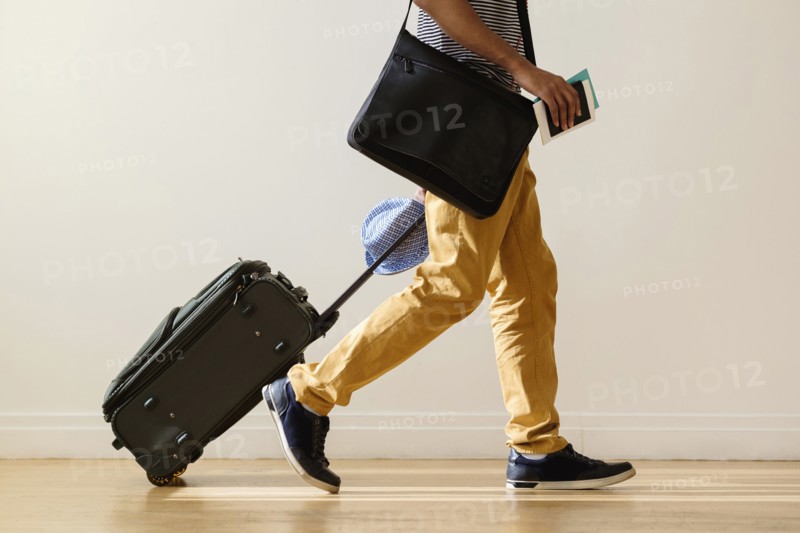 Black businessman rolling luggage