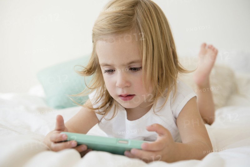 Caucasian girl using cell phone on bed