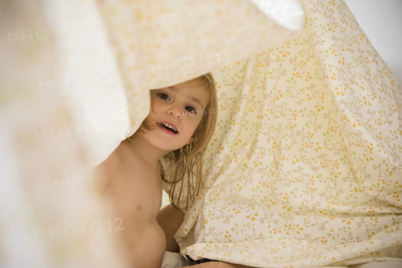 Caucasian girl playing under blankets