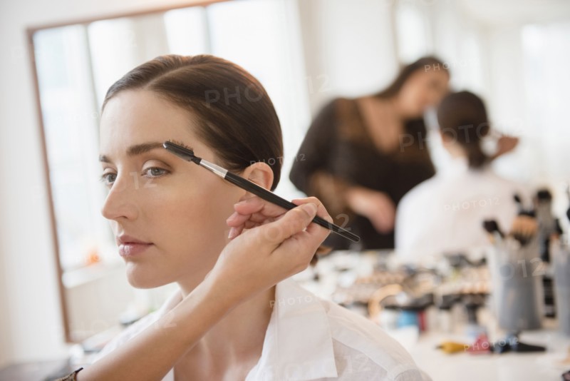 Woman having makeup applied by stylist