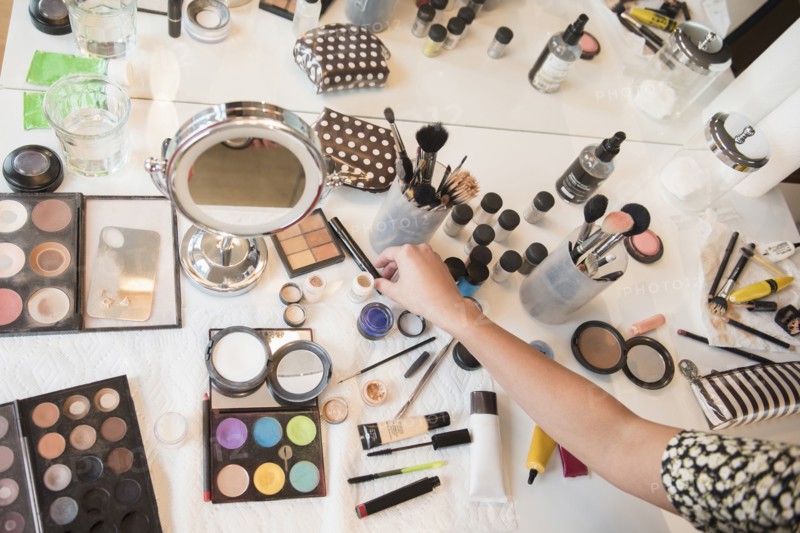 Hispanic woman selecting makeup from table