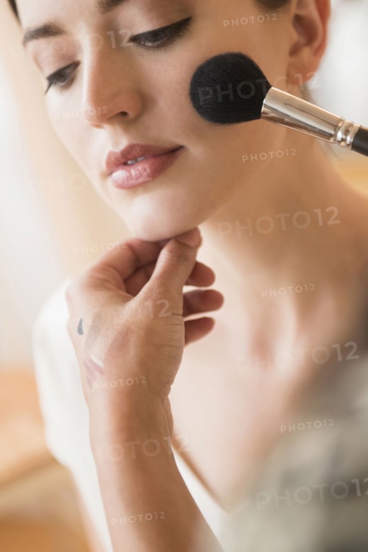 Woman having makeup applied by stylist