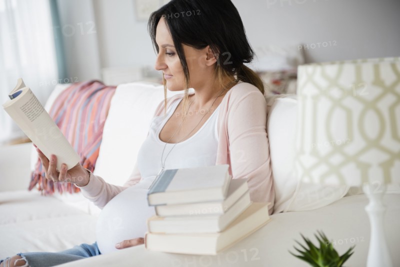 Pregnant Caucasian woman reading baby books