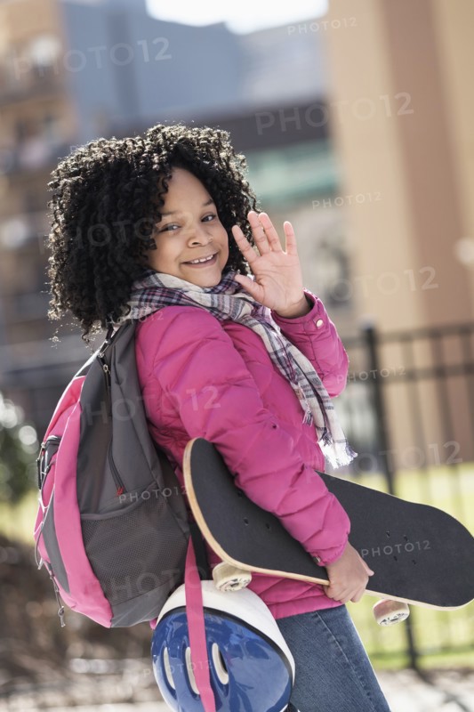 African American girl carrying skateboard outdoors