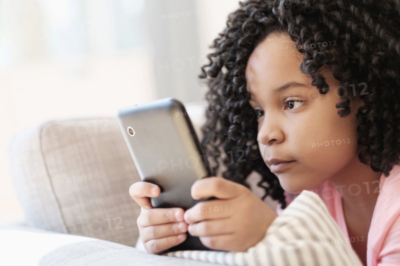 African American girl using cell phone on sofa