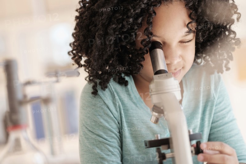 African American girl using microscope in science classroom