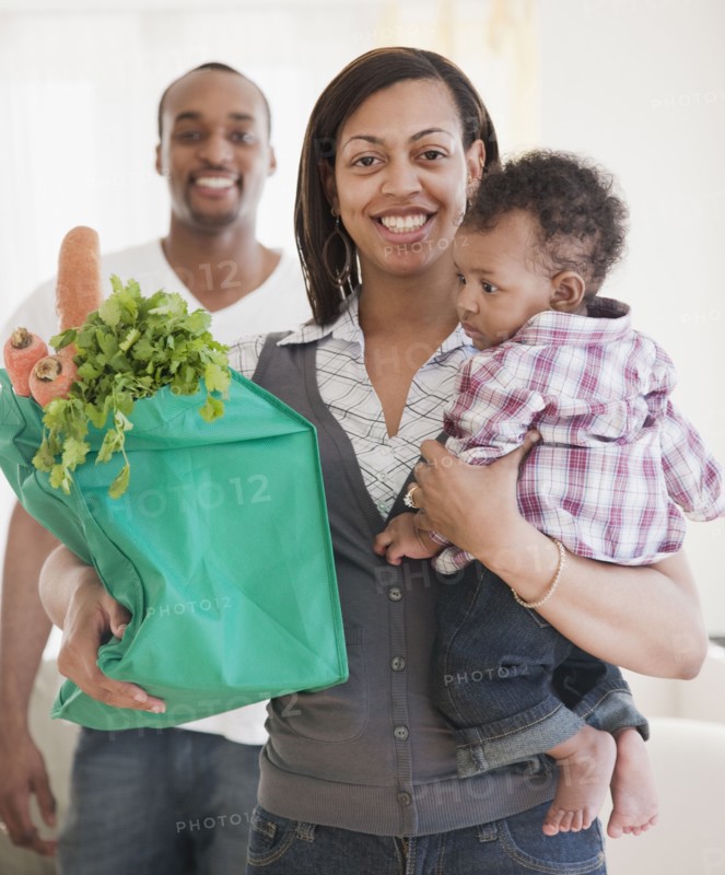 African couple holding baby and groceries in reusable bag