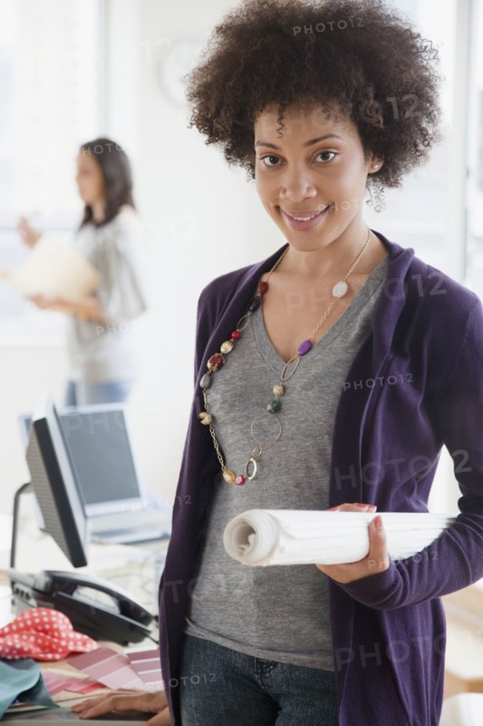 Mixed race woman holding blueprints in office