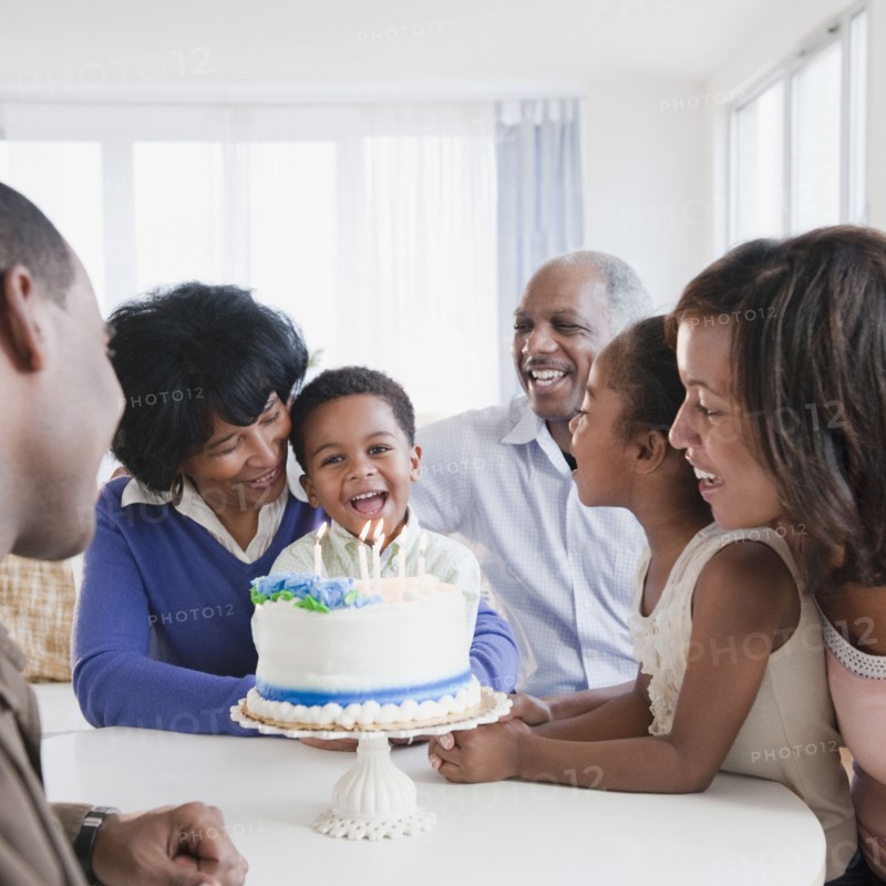 African American family watching grandson blow out birthday candles
