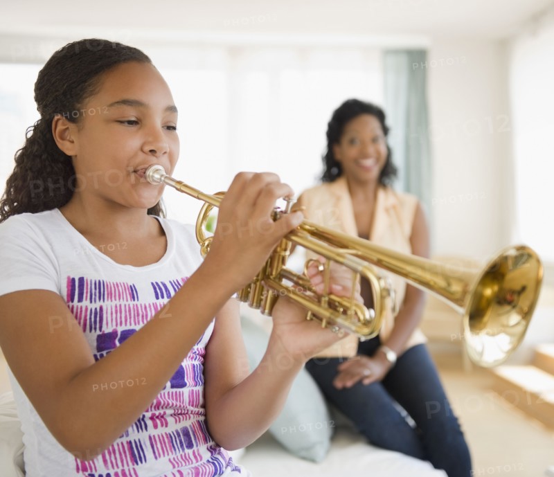 Mother watching daughter playing trumpet
