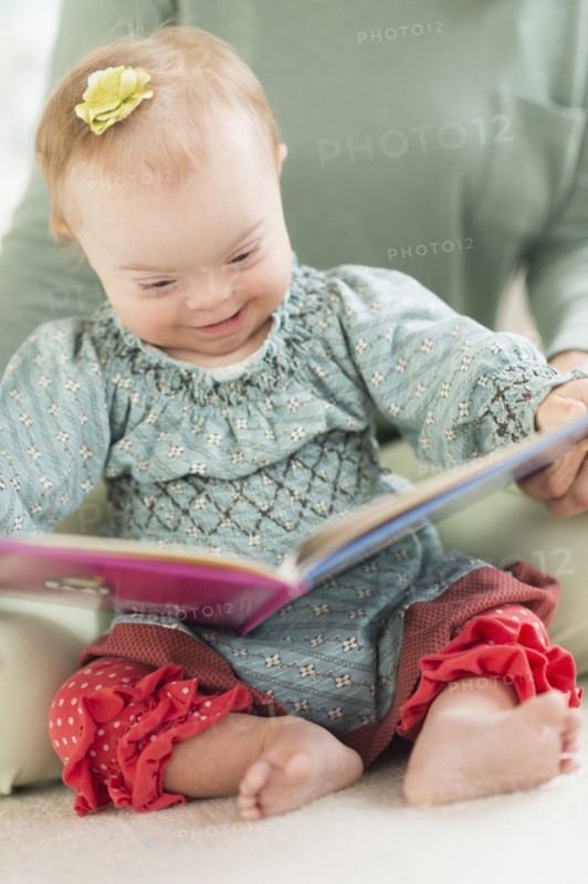 Caucasian baby girl with Down Syndrome reading