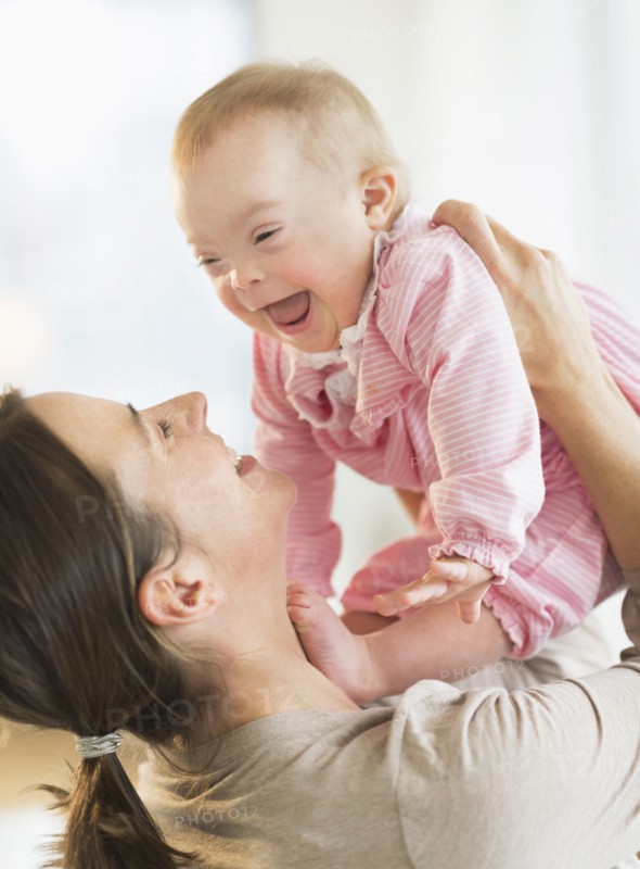 Caucasian mother playing with baby girl with Down Syndrome
