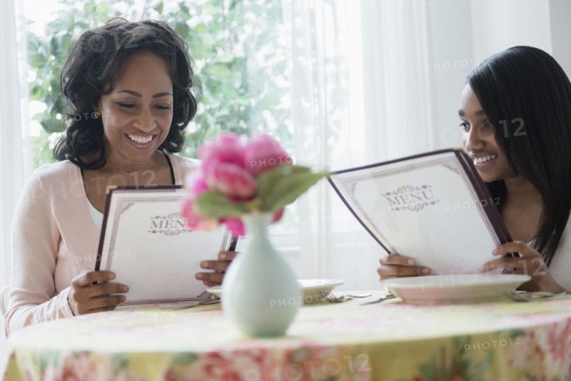 Mother and daughter reading menus in restaurant