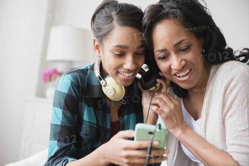 Mother and daughter listening to cell phone music on headphones