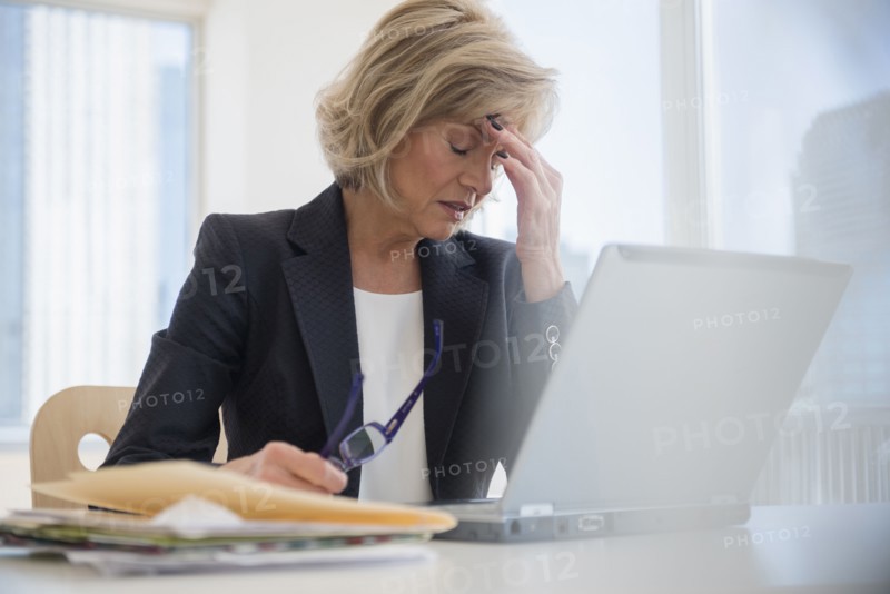 Caucasian businesswoman with headache using laptop