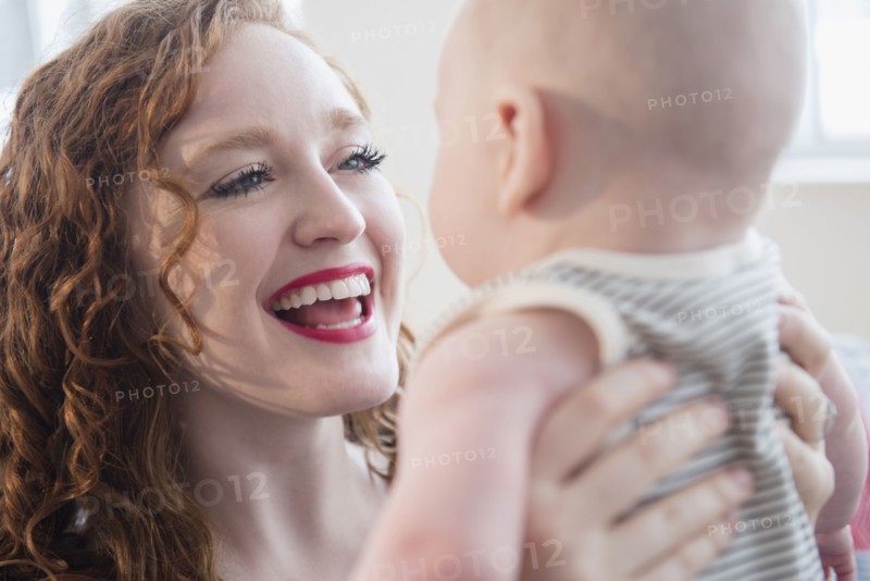 Caucasian woman holding baby son face to face
