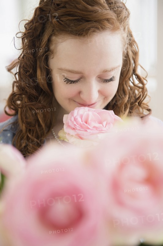 Caucasian woman smelling pink rose