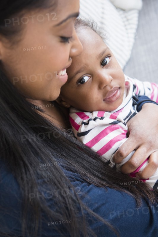 Black mother cuddling baby daughter