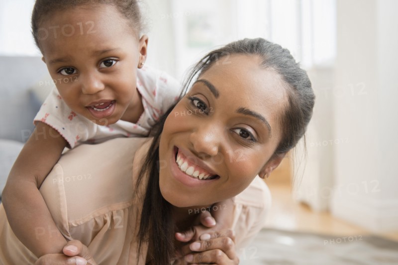 Black mother carrying baby daughter piggyback