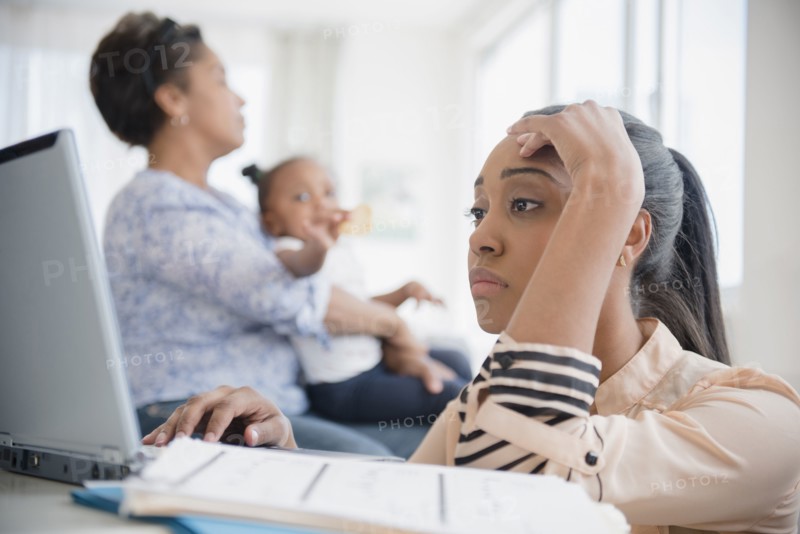Stressed Black woman paying bills using laptop