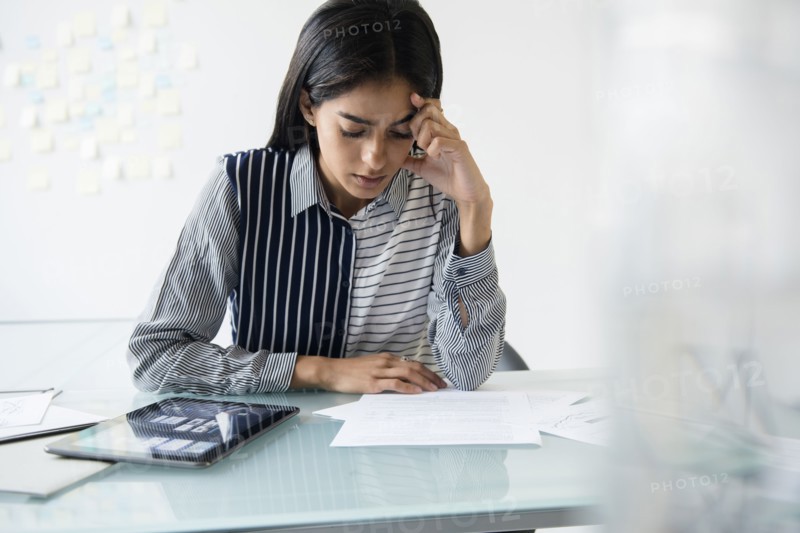 Indian businesswoman reading paperwork in office