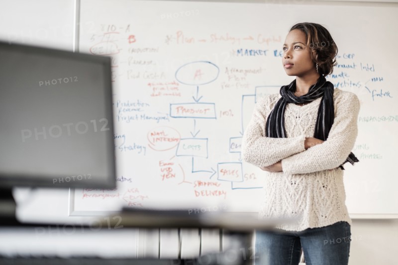 Pensive Black businesswoman thinking in office near whiteboard