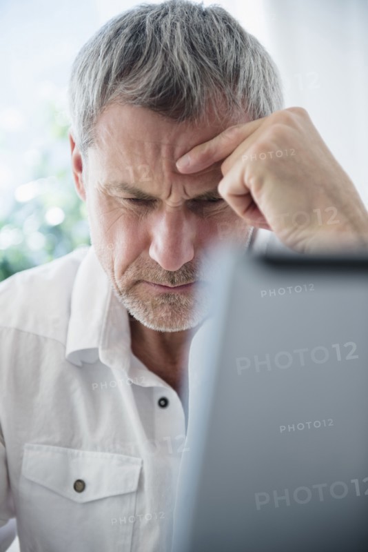 Frustrated older Caucasian man using laptop