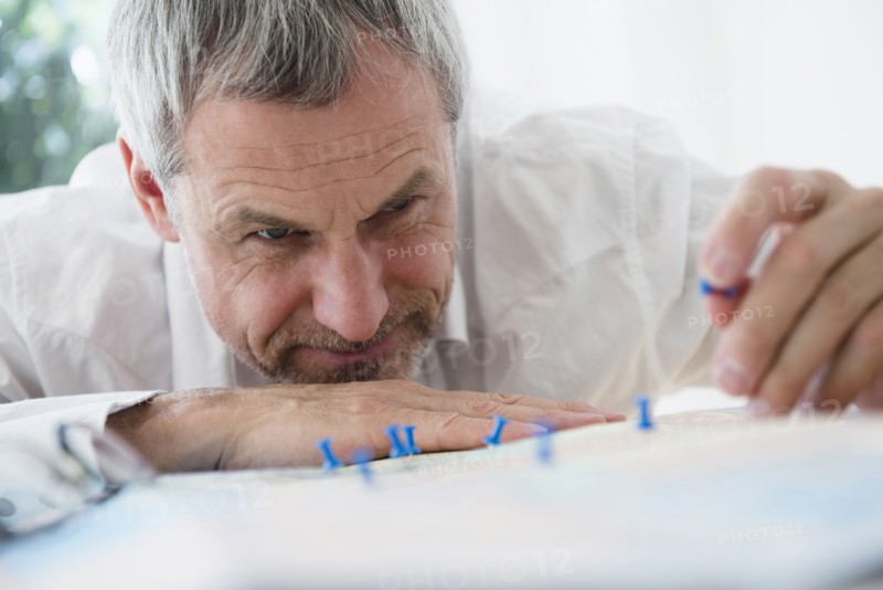 Older Caucasian man sticking pins in map