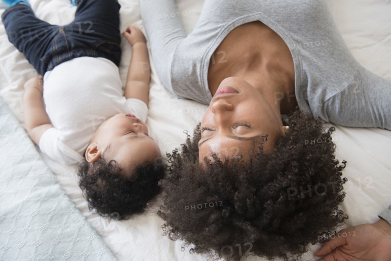 Mother and baby son sleeping on bed