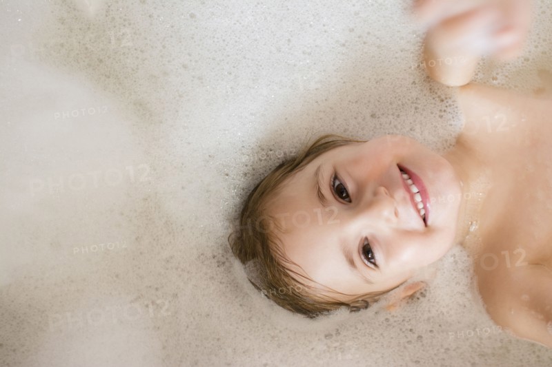 Caucasian girl smiling in bubble bath