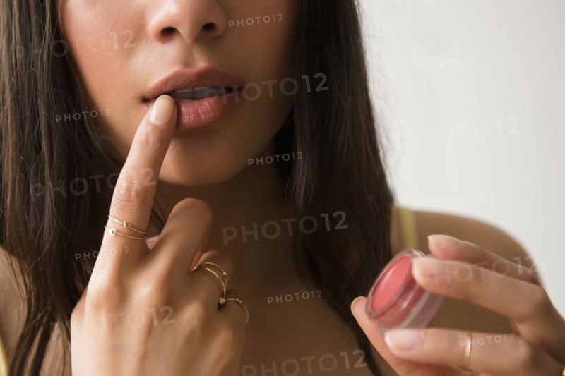Hispanic woman applying lip gloss